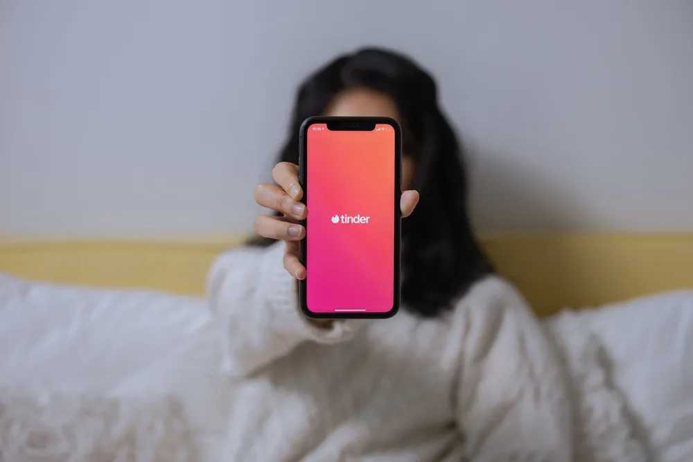 Jeune femme tendant son téléphone avec l'application Tinder.
