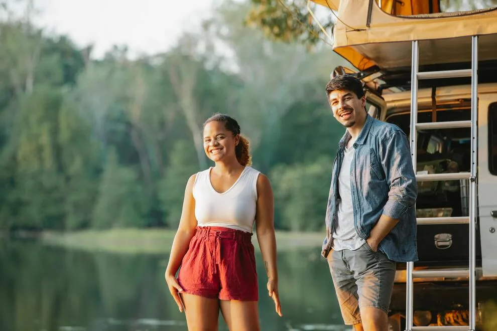 Une jeune femme et un jeune homme souriant au bord d'un lac
