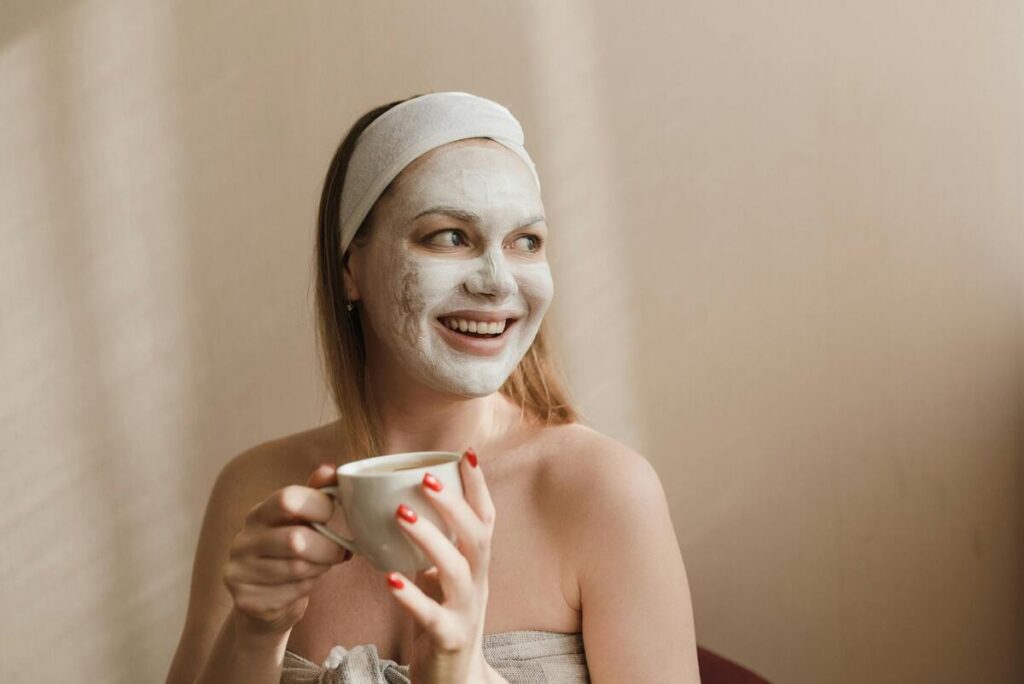 Jeune femme souriant avec un masque sur le visage, tenant une tasse de thé