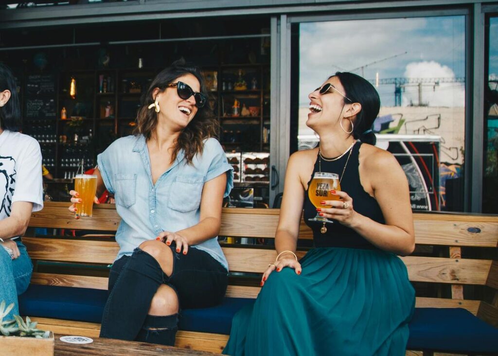 Deux copines buvant un verre en terrasse et rigolant