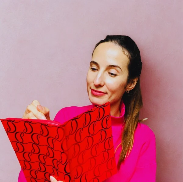 Photo de Anaëlle Adam, rédactrice web seo freelance, en train d'écrire dans un carnet rouge.