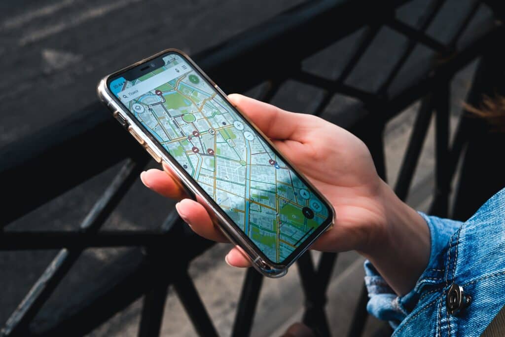 An outdoor close-up of a hand holding a smartphone displaying a map application.